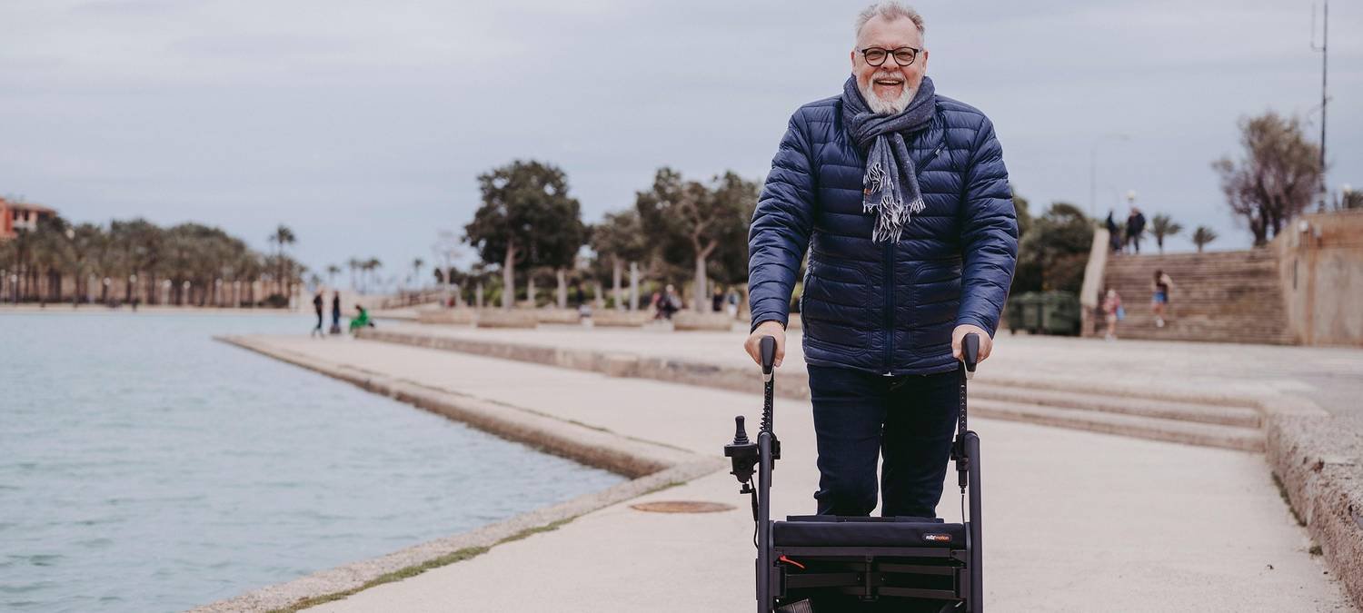 Smiling older man outdoors by the water with his walker