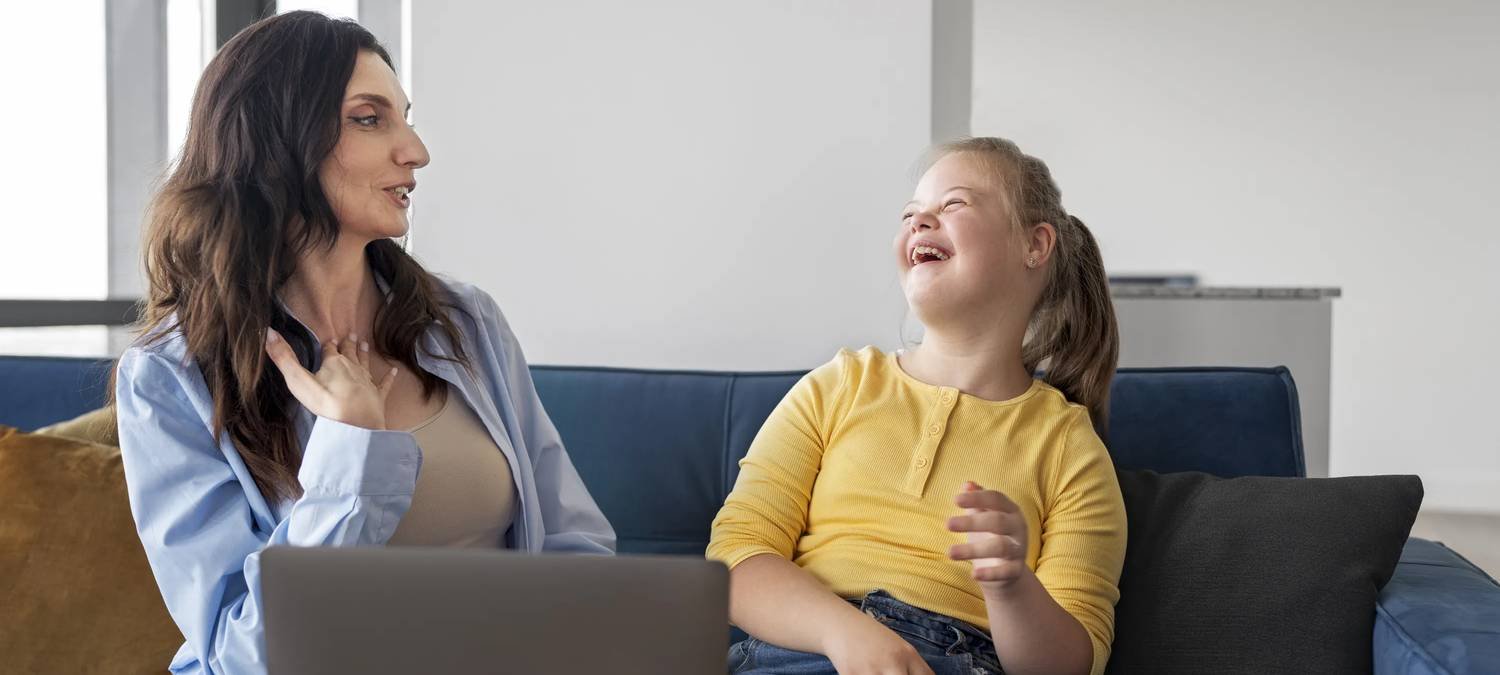 Woman and young girl laughing together on a couch