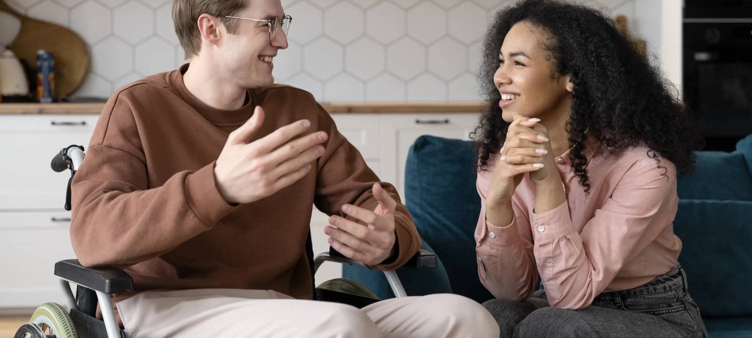 Support worker and participant laughing together during a conversation at home